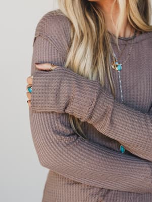 Person wearing a brown sweater with a neutral background