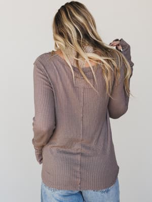 Person wearing a brown textured sweater against a plain background