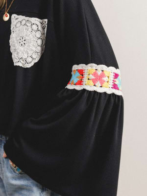 Close-up of sleeve detail on black boho top with lace detailing
