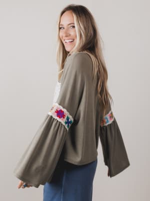 Woman wearing a green cardigan with colorful sleeve trim against a plain background