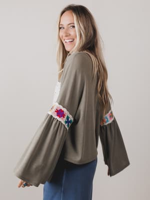 Woman wearing a green cardigan with colorful sleeve trim against a plain background