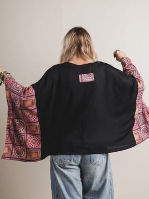 Back view of woman wearing a black boho top with red patterned fabric on the sleeves