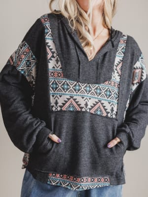 Person wearing a dark gray hoodie with colorful geometric patterns on a plain background