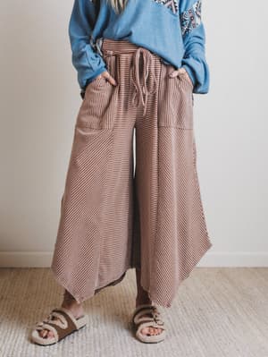 Person wearing brown striped pants and a blue sweater on a plain background