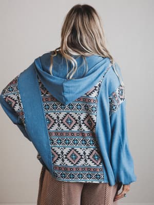 Person wearing a blue hoodie with a patterned back on a plain background