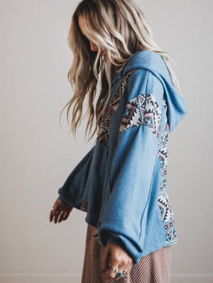 Person wearing a blue embroidered hoodie with a neutral background