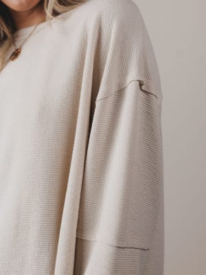 Close-up of a beige textured sweater on a neutral background