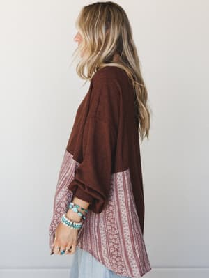 A side-profile shot of a relaxed patchwork top in deep cacao and dusty rose floral stripe, styled with stacked turquoise bracelets and light wash denim — the kind of top that looks like it was always yours.