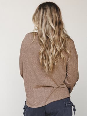 A back-view studio shot of a model wearing a relaxed heathered mocha long sleeve top with a soft, drapey fit paired with navy cargo pants — easy, lived-in, and the kind of top you reach for without thinking.