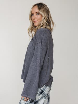 A relaxed oversized long sleeve top in heathered charcoal, styled with plaid pants and a turquoise ring stack — the kind of effortless, cozy outfit that looks intentional without trying.