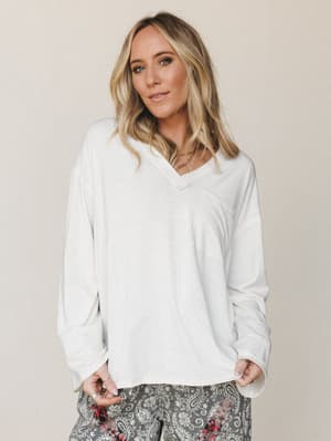 A relaxed, oversized long-sleeve top in warm natural white paired with paisley pants — the kind of effortless outfit that makes a Saturday morning feel intentional.