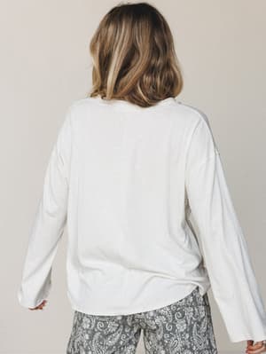 A relaxed back-view shot of a cream long-sleeve top paired with grey paisley wide-leg pants — effortlessly lived-in and the kind of outfit you reach for without thinking twice.