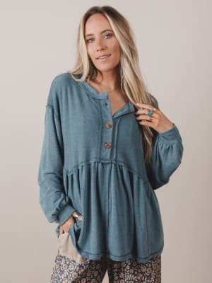 Woman wearing a blue long-sleeve top with buttons against a plain background