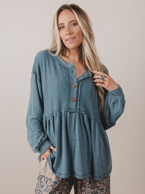 Woman wearing a blue long-sleeve top with buttons against a plain background