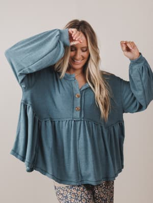Woman wearing a blue long-sleeve top with a plain background