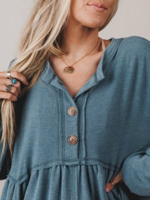 Woman wearing a blue denim dress with a necklace and rings.