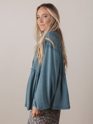 Woman wearing a teal jacket against a beige background