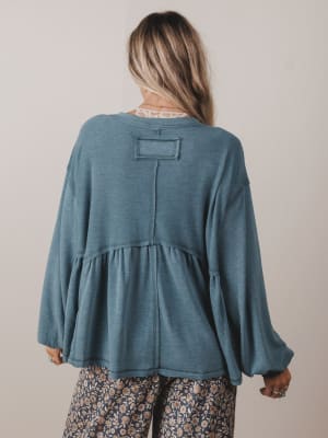 Person wearing a blue long-sleeve top with a plain background