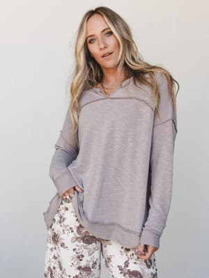 A relaxed, lived-in pullover in muted taupe pairs effortlessly with floral wide-leg pants — the kind of outfit that looks like you tried just enough, and felt great doing it.