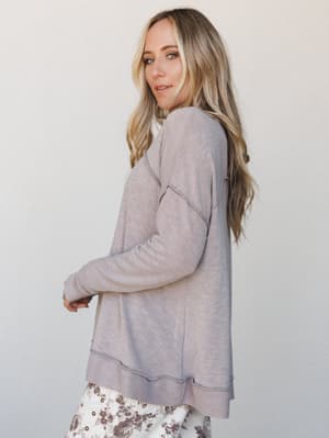 A soft, lived-in pullover sweater in dusty lavender-taupe is styled with floral pants for an effortlessly cozy, put-together look — the kind of outfit that works just as hard on a slow morning as it does running errands.