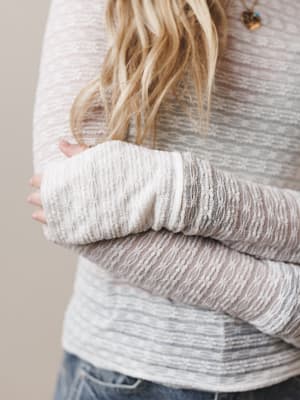 Person wearing a layered sweater with a neutral background