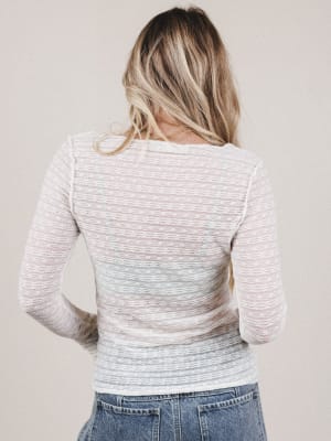 Person wearing a light gray sweater with a subtle pattern on a plain background