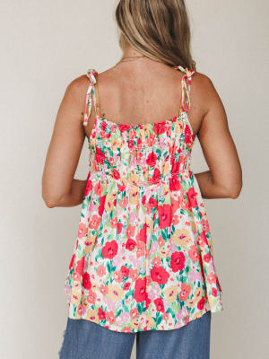 A flowy floral cami top shot from behind, all smocked bodice and tie straps and garden-party energy — the kind of top that makes even a Tuesday feel intentional.