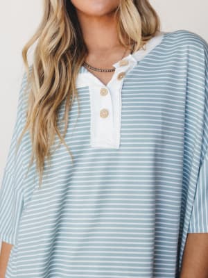 A relaxed, oversized henley top in dusty mint stripe shot close-up on a model — the kind of top that looks equally good thrown on for a coffee run or a lazy beach morning.