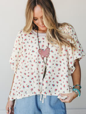 A relaxed, flutter-sleeve top in cream with a ditsy floral print worn with light blue pants — the kind of outfit that makes a Tuesday feel like something worth remembering.
