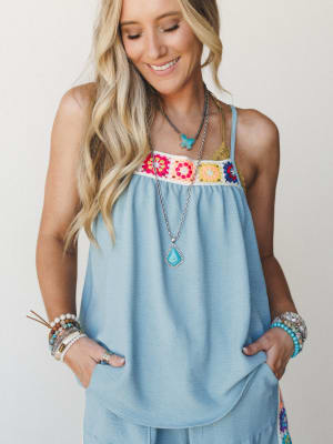 A breezy spaghetti-strap tank with a colorful granny square crochet chest panel, styled with stacked bracelets, layered turquoise necklaces, and matching wide-leg pants — effortless and a little handmade-feeling in the best way.
