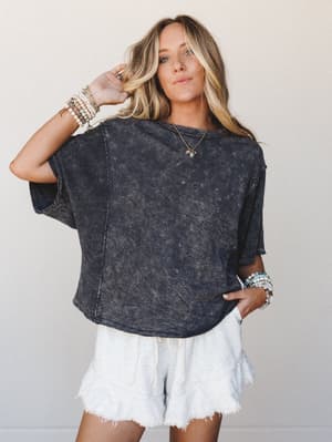 A relaxed, lived-in mineral-washed charcoal tee paired with raw-hem white shorts — the kind of effortless outfit that looks like you didn't try but absolutely did.
