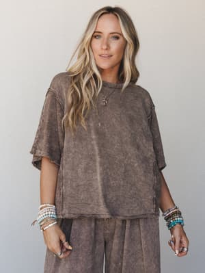 A lived-in mineral-washed top in mocha paired with matching wide-leg pants, styled with stacked beaded bracelets and a delicate pendant necklace — the kind of effortless set that looks like you planned it without trying.