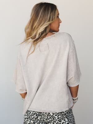 A back-view shot of a relaxed, oversized textured top in washed taupe paired with leopard print pants — the kind of effortless combo that looks like it took no effort but absolutely did.