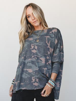 An oversized camo top in muted army tones styled with stacked boho bracelets and layered gold necklaces — the kind of effortless outfit that looks like you tried just enough.