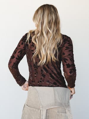 Shot from the back, a model in a rich brown floral burnout mesh long-sleeve top is paired with khaki corduroy wide-leg pants — the kind of outfit that feels effortlessly put-together without trying too hard.