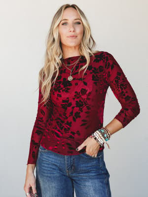 A deep wine velvet-flocked floral long sleeve top styled with denim and layered boho jewelry — the kind of top that makes a Tuesday feel intentional.