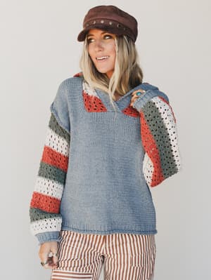 Person wearing a colorful crochet sweater with a plain background