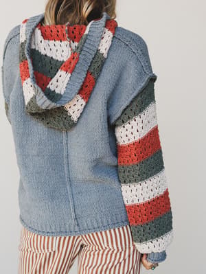 Person wearing a blue jacket with a colorful striped scarf on a plain background