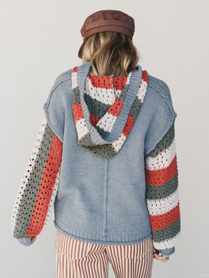 Person wearing a colorful crochet sweater with a plain background