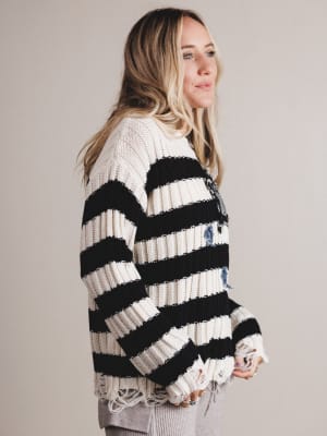Woman wearing a black and white striped sweater with a neutral background