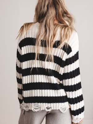 Person wearing a black and white striped sweater with a neutral background