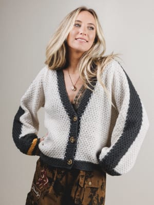 Woman wearing a white and black striped cardigan with a neutral background