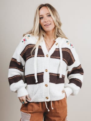 Woman wearing a patterned cardigan with a neutral background