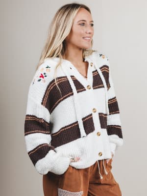 Woman wearing a plaid cardigan with white trim on a plain background
