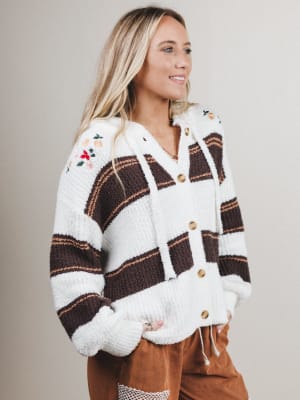 Woman wearing a plaid cardigan with white trim on a plain background