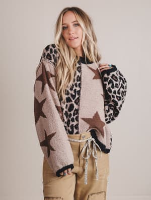 Woman wearing a patterned sweater with stars and leopard print on a plain background