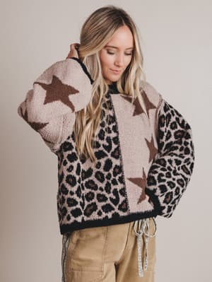 Woman wearing a patterned sweater with stars and leopard print on a plain background