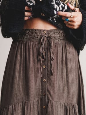Brown button-up skirt with a black cropped sweater on a neutral background