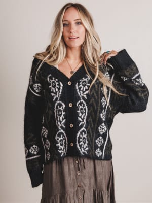 Woman wearing a black patterned sweater against a plain background