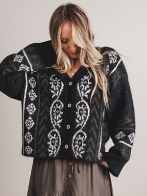 Woman wearing a patterned cardigan with a neutral background